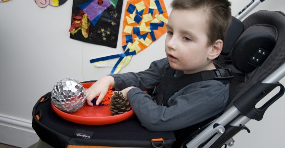 Image of young boy in a buggy playing with sensory items on a Trabasack Curve Connect play tray
