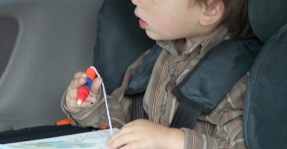 Young boy sits in a car seat using the Trabasack Mini Connect as a play tray