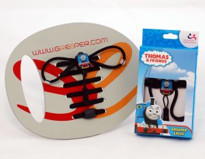 Photograph shows a packaged pair of Thomas the Tank Engine Greeper shoe laces, and a pair of example laces threaded through a cardboard display board