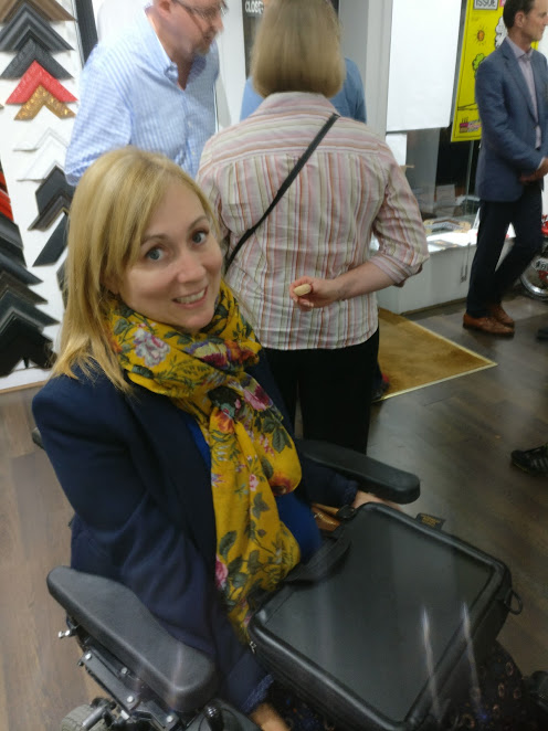 Clare Edwards inventor of the trabasack wheelchair tray using it at a private view at a gallery