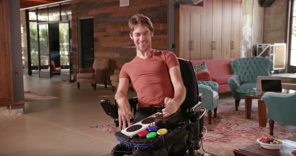 Zach Anner plays a video game in a spacious American lounge, using a Trabasack Curve Connect lapdesk and accessible gaming accessories