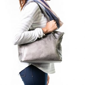 Photograph shows the side-view of a woman with a Metallic Grey Samantha Renke bag over the shoulder.