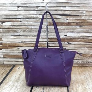 Image of a large ladies shoulder bag in a bold purple colour in front of and atop of a wooden background