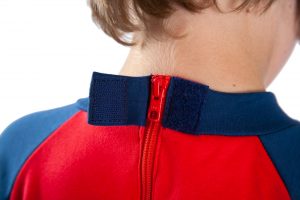 Image shows a photograph of the back of a boy's neck and shoulders, to illustrate the opening of the velcro cover for the hidden zip on the back of a Seenin sleepsuit in navy and red