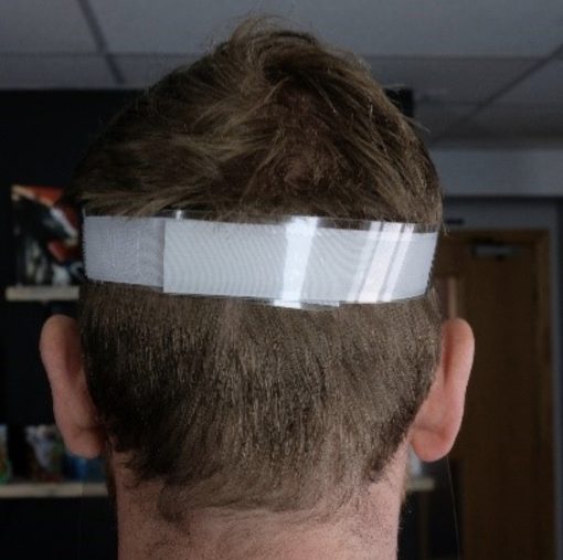 Image is a photograph showing the back of a man's head whilst wearing a Hydrate for Health full face visor, to illustrate the adjustable, velcro-fastening head band