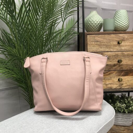 Image is a photograph of the Samantha Renke accessible handbag in Blush on a white table in a modern living room