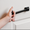A hand of a wheelchair user grasping the t-pull to close the white door